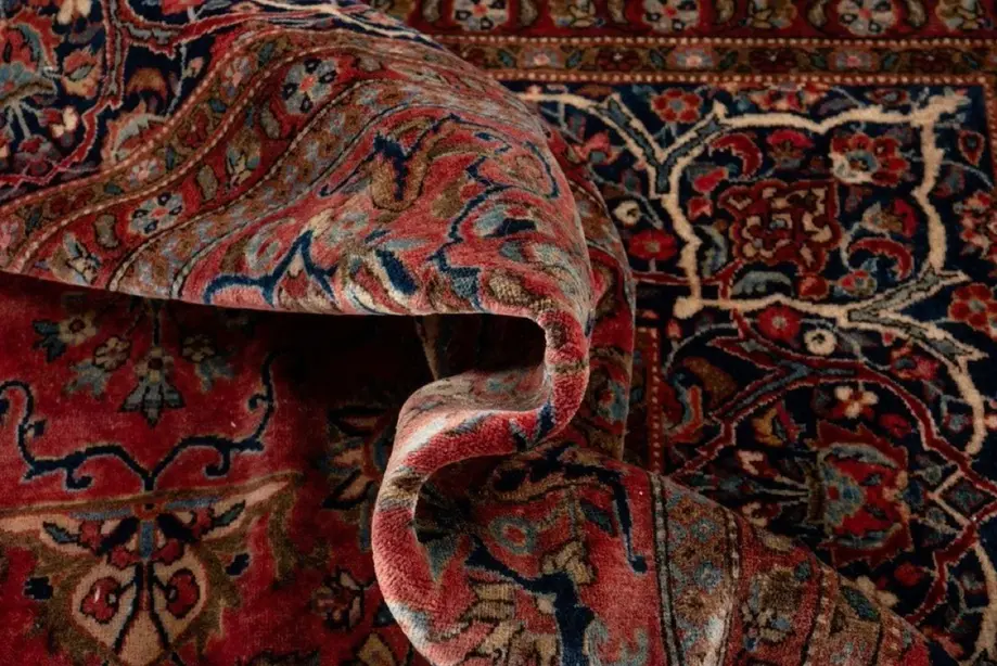 Close-up of a folded Persian rug in deep red and blue.